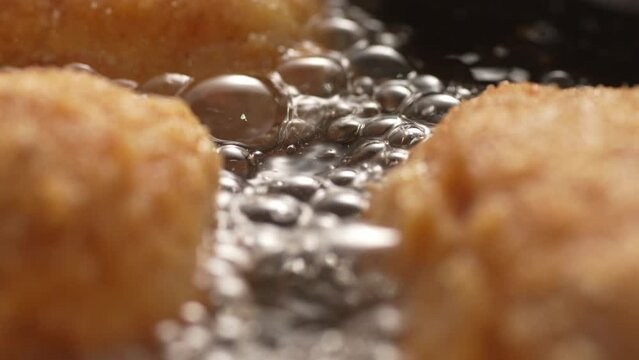 Boiling oil bubbles between Breaded Cutlets in Frying Pan. Close-up, shallow dof.