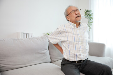 senior man suffering from back pain on sofa
