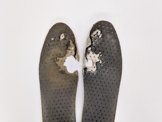 Two old, shabby orthopedic insoles isolated on white background. Dirty leather insoles. Worn out things with holes. Inner soles of shoes. Top view banner close up.