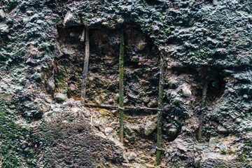 Steel reinforcement in a dilapidated concrete wall as a picturesque background.