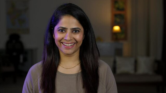 A beautiful young woman looking up to the camera and smiling charmingly - smiling woman  wheatish skin  Asian girl. A happy young adult girl with an attractive face: excitement  celebration  colleg...