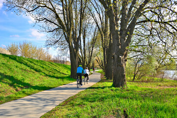 Cyclists riding down a pathway in a park in spring sunny day. Velo Dunajec cycling road in Nowy Sacz, Poland