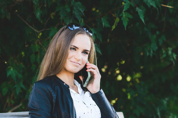 Young beautiful smiling woman talking on cell phone at public park.Summertime.