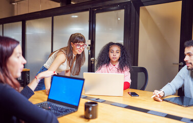 multiracial group of young students or businesspeople sitting in co-working space working	