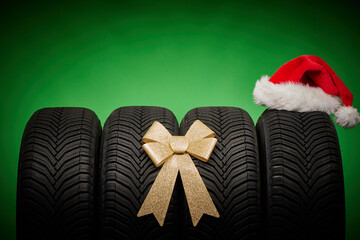 Car tires, new tyres, winter wheels isolated on green christmas background with bow ribbon present...