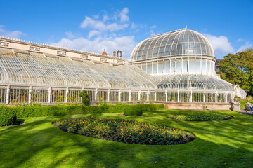 Fototapeta na wymiar Exterior view of Palm House, a cast iron glasshouse designed in the 19th century by Charles Lanyon, in the Botanic Gardens near Ulster Museum, Belfast, Northern Ireland.