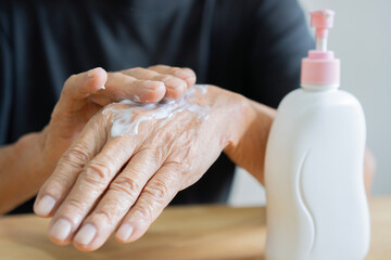 Close up hands of an older man applying cream. Antiaging skin body care concept.