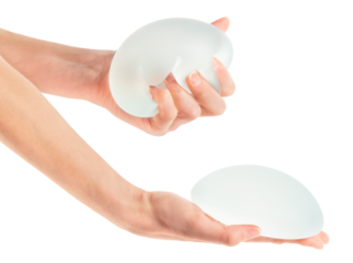 Female squeezing soft breast implant in hand on white background. Aesthetic surgery.