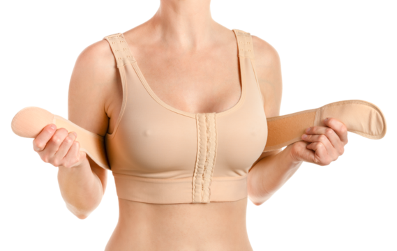 Woman wearing compressing bra with a stipe after breast augmentation