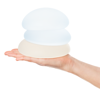 Female shows stack of breast implants in hands isolated on white background