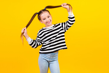 Photo of excited carefree little child dressed striped pullover arms ponytails empty space isolated yellow color background