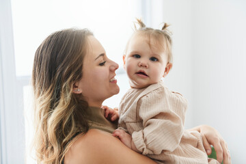 young beautiful mother with a baby girl having great time at home