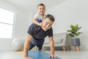 Little boy child having workout together with his father, exercising with dumbbells at home