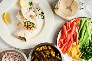 Beef and Lamb Lebanese style shawarma with onions, greens and vegetables such cucumber and tomato. all seasoned with tahini and garlic sauce and wrapped in pita or pita bread.