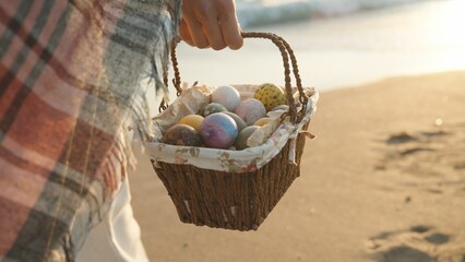 A young woman walks along the beach at sunset carrying a basket of Easter eggs. I'm walking towards...