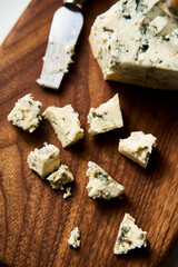 Gorgonzola cheese on wood board with cheese knife and fork. On white marble background