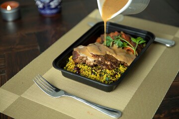Pouring gravy over meal