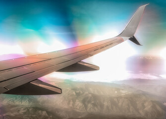 wing of a civilian airliner airplane in flight with mountains with optical effect