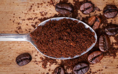 Coffee beans and ground seeds on a spoon. Caffeine in coffee is a drug that stimulates the brain and nervous system.