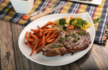 Grilled steak with chimichurri, steamed vegetables and sweet potato fries