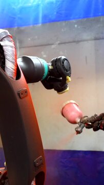 Industrial painter painting a robotic arm with spray