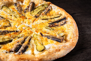 delicious pizza with sprats fish and pickled cucumber on wooden background