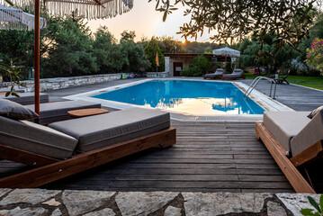 Swimming pool and beds for relaxing in summer. Swimming pool in the nature among greenery.