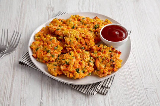 Homemade Carrot Corn Fritters with Ketchup on a Plate, side view.