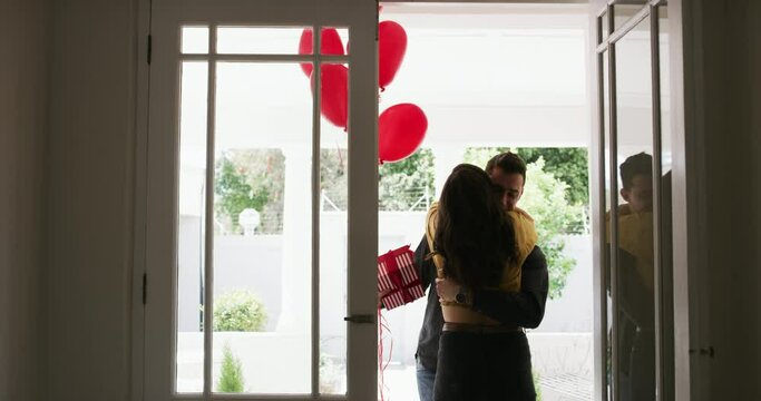 Man, balloons and surprise at door, happy woman and hug boyfriend for anniversary celebration. Birthday gift, romance and couple for love, present and valentines day with romantic gesture and box