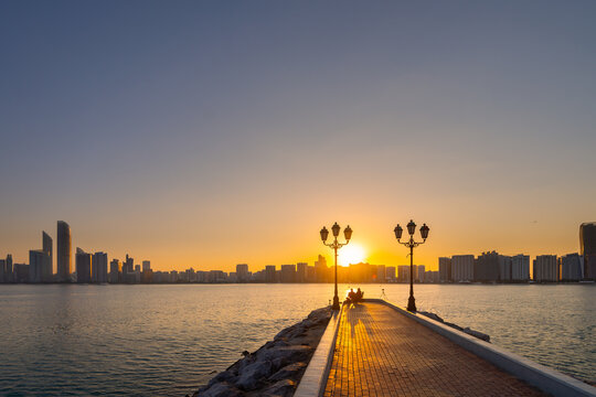 Fototapeta sunrise overlooking city scape, people relaxing in the capital city of Abu Dhabi