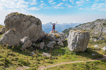 young woman hiker with outstretched arms, standing between big rocks at Rofan alps