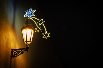 Illuminated historic street lamp with decorative Christmas decorations.