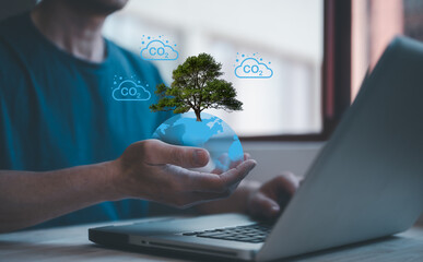 carbon emission concept businessman hand holding virtual glob and tree working on computer laptop, carbone footprint and carbon credit for green business - obrazy, fototapety, plakaty
