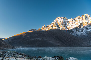 View of Lake Gokyo and snow capped mountains in Gokyo settlement at dawn during trekking to Everest...