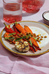 Healthy Homemade Roasted Carrots Ready to Eat with yougurt sause, vegan, vegatarian homemade food on pink backround. Vertical