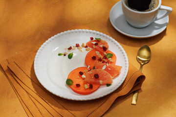 Healthy breakfast concept. Oatmeal, quinoa granola with yogurt, dried fruit, seeds, honey, persimmon in white plate on yellow background, top view, copy space. Allergy-friendly, gluten free concept