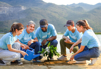 group of diverse people in unity volunteer T-shirt are planting trees at sand beach by the river,concept of volunteering,reforestation,conservation of natural resources and the environment