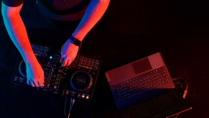 DJ's Hands Adjusting Sound Mixer Under Club Lights