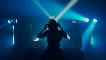 Fototapeta na wymiar Female DJ Leading the Party at Nightclub with Crowd in Silhouette