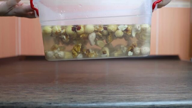 Soaking nuts. Girl shows dirty seeds. Chemical processing of food. Digestive problems are caused by intolerance peanuts, allergies cashews, hazelnuts. Allergic reaction phytic acid. Before and after