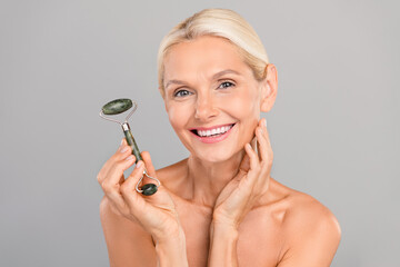 Photo of charming pretty old woman naked shoulders doing skincare massage isolated grey color...