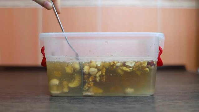 Soaking nuts. Girl shows dirty seeds. Chemical processing of food. Digestive problems are caused by intolerance peanuts, allergies cashews, hazelnuts. Allergic reaction phytic acid. Before and after