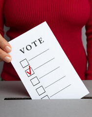 A hand throws a ballot into a box on Election Day. Voting concept.	