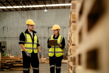 workers man and woman engineering walking and inspecting timbers wood in warehouse. Concept of smart industry worker operating. Wood factories produce wood palate.