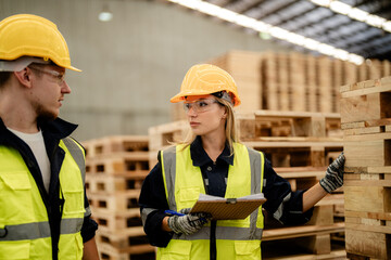 workers man and woman engineering walking and inspecting timbers wood in warehouse. Concept of smart industry worker operating. Wood factories produce wood palate.