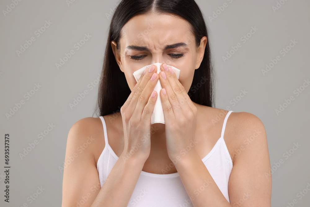 Canvas Prints Suffering from allergy. Young woman blowing her nose in tissue on light grey background