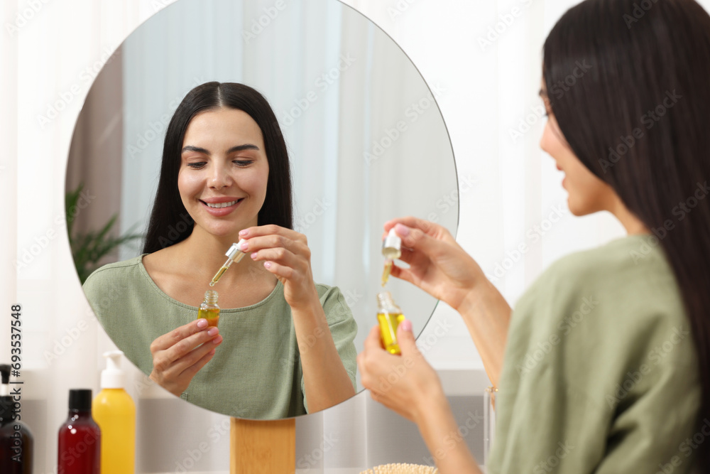 Sticker Beautiful woman holding bottle of serum in room. Cosmetic product