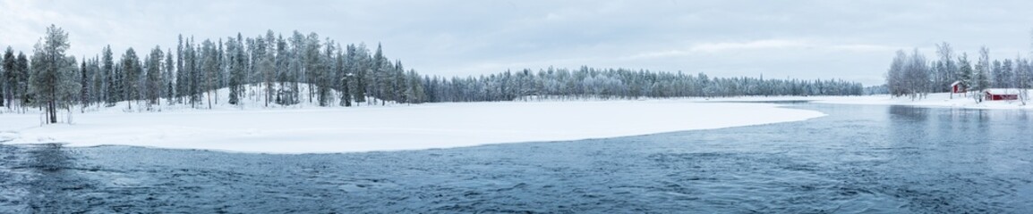 Winter in Finland: landscape in ultra panorama format with river in snow covered boreal forest