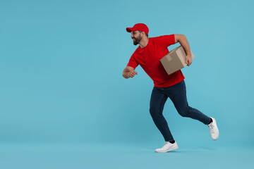 Happy young courier running to deliver parcel on light blue background, space for text