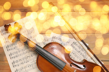 Fototapeta premium Christmas and New Year music. Violin and music sheets on wooden background, bokeh effect